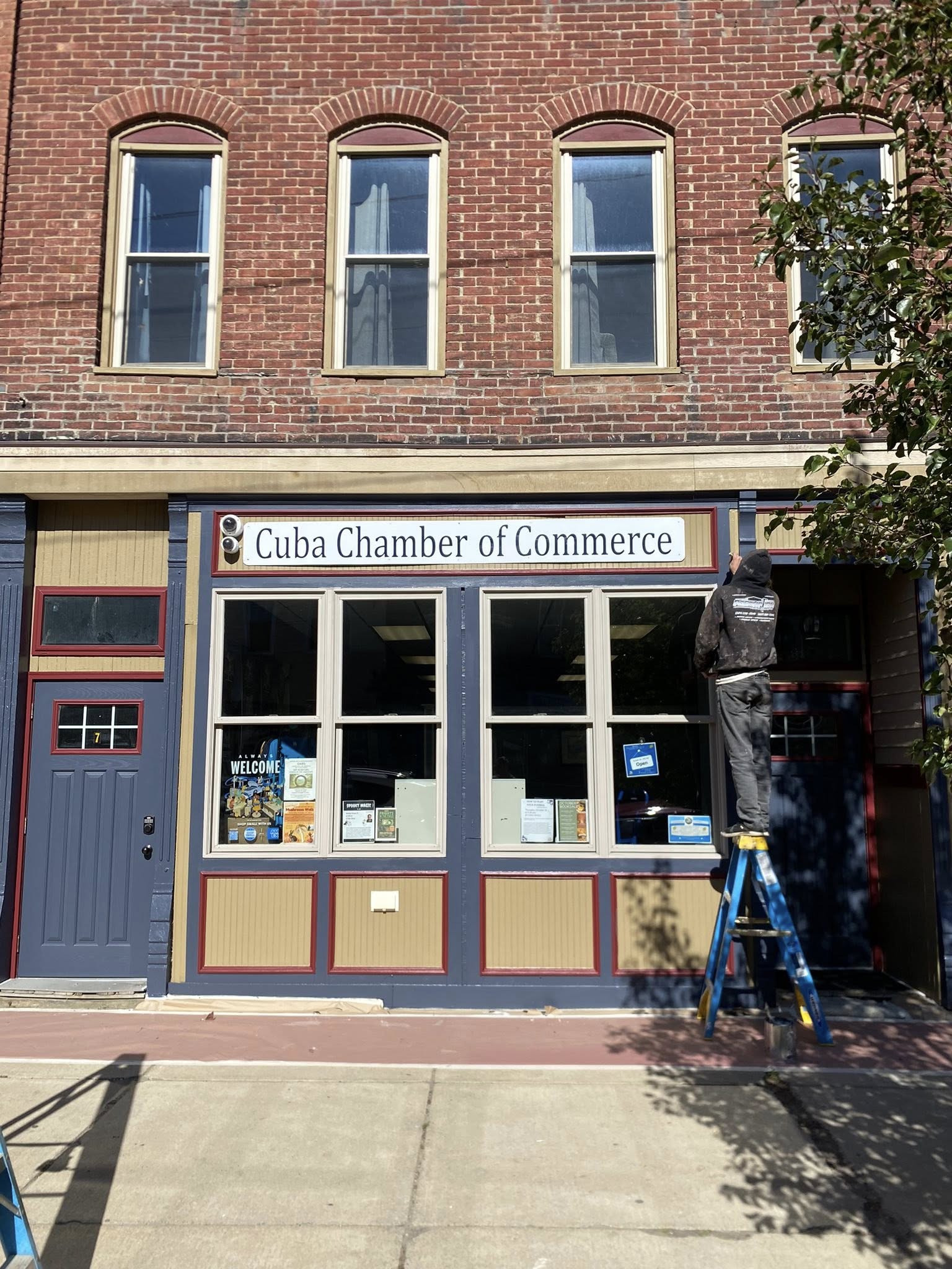 Painter working on the Cuba Chamber of Commerce storefront exterior